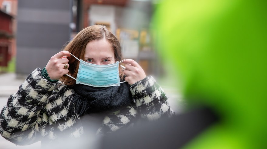 Kvinna tar på munskydd