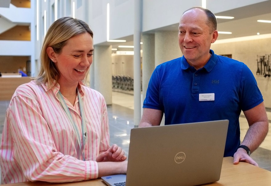 Agnes och Hans som gått utbildningen i kvalitetsdriven verksamhetsutveckling står tillsammans vid en laptop.