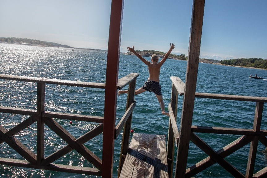 Pojke hoppar i havet från brygga