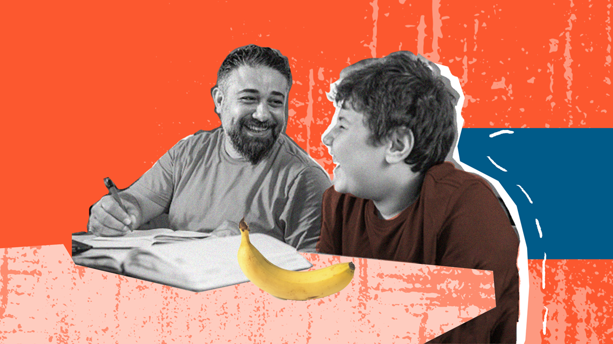 En man och en pojke sitter vid ett bord med en bok och en banan.